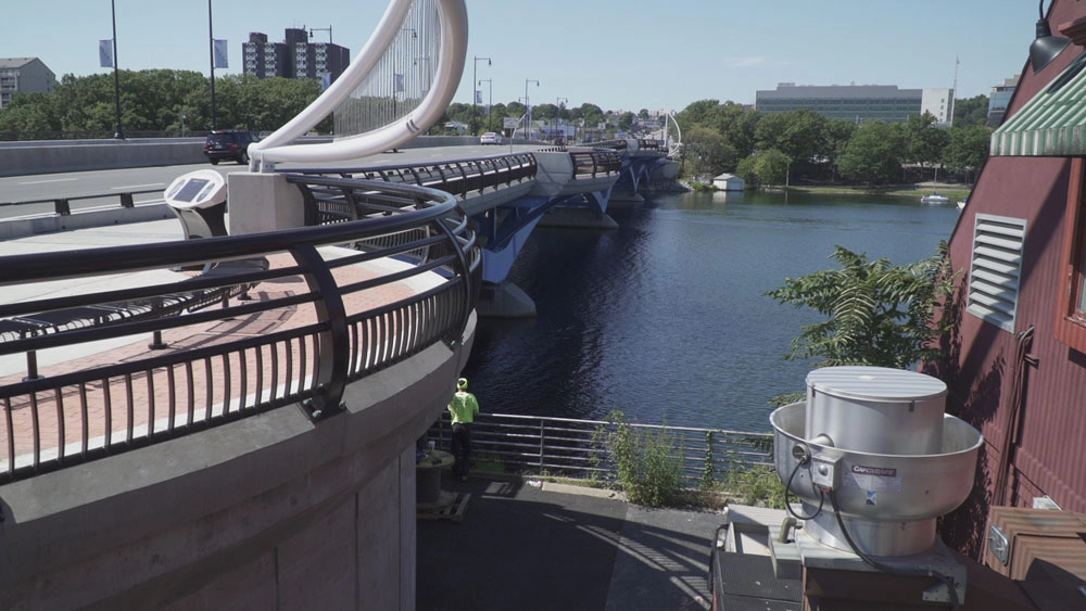 The construction of the Kenneth F. Burns Memorial Bridge was a complex and high-profile project that replaced a structurally deficient, 7-span concrete arch bridge built in 1916 with 2 new bridges over Lake Quinsigamond, between Worcester and Shrewsbury, MA. The new bridges are 870’ long, 5-span open spandrel steel deck arches founded on 36” diameter pipe piles up to 290’ deep. The project also included reconstructed portions of Lake Avenue and Route 9 and contains many architectural features.